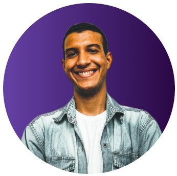 Foto de Bruno Souza sorrindo, com o fundo roxo, usando jaqueta jeans azul claro e camisa branca.